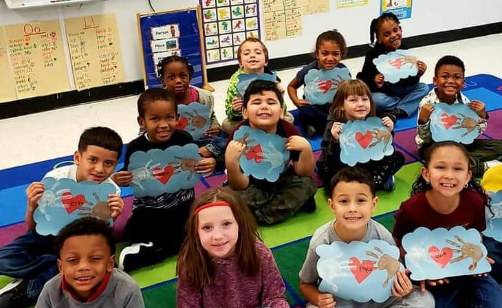 Students in classroom holding paper crafts